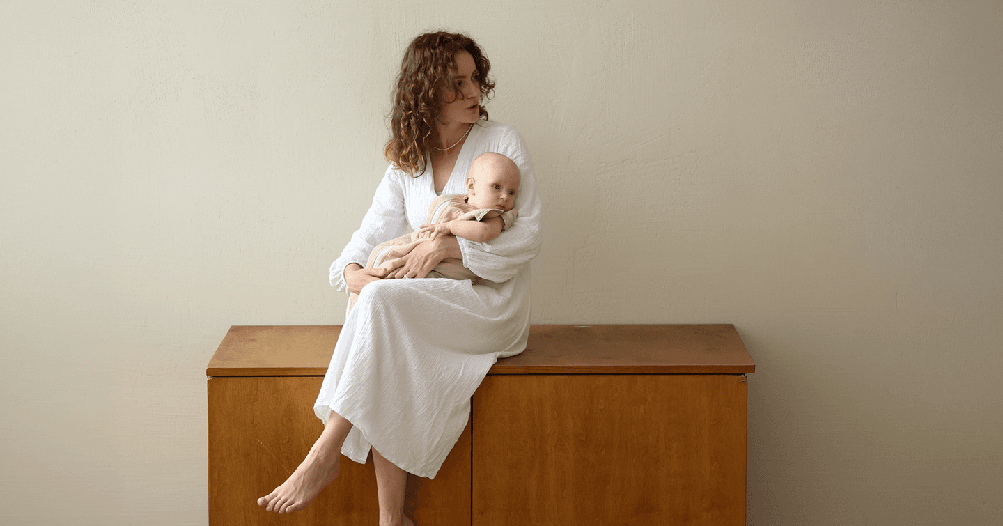 Mother sitting with her baby, both dressed in white