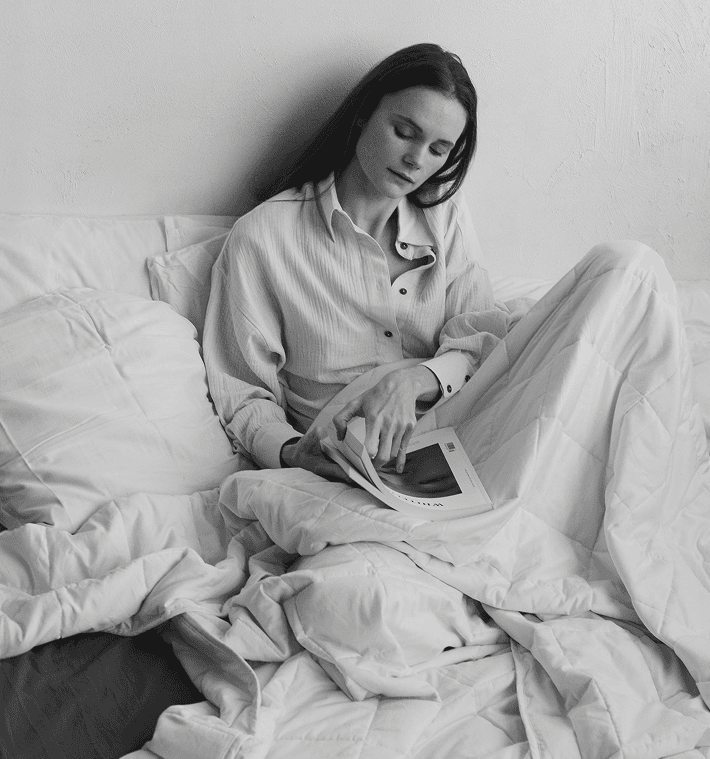 Woman relaxing under a Lullaboo weighted blanket